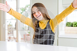 Young beautiful blonde kid girl wearing casual yellow sweater at home looking at the camera smiling with open arms for hug