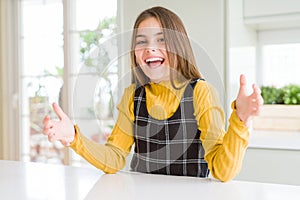 Young beautiful blonde kid girl wearing casual yellow sweater at home smiling cheerful with open arms as friendly welcome,