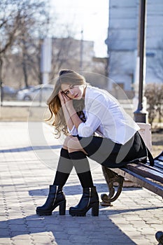 Young beautiful blonde schoolgirl sitting on a bench