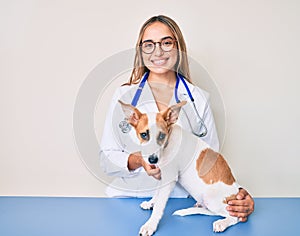 Young beautiful blonde veterinarian woman checking dog health smiling with a happy and cool smile on face