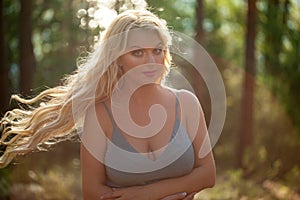 Young beautiful blonde woman in blue dress - neglegee pegnoir underwear posing in forest
