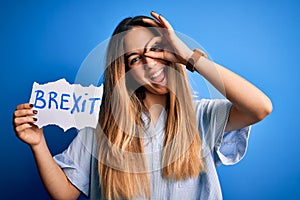 Young beautiful blonde woman with blue eyes holding banner with brexit message with happy face smiling doing ok sign with hand on