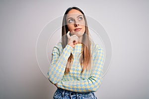 Young beautiful blonde woman with blue eyes standing over isolated background with hand on chin thinking about question, pensive