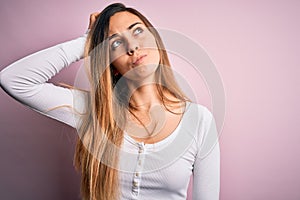 Young beautiful blonde woman with blue eyes wearing white t-shirt over pink background confuse and wondering about question