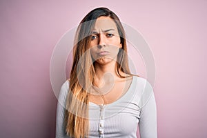 Young beautiful blonde woman with blue eyes wearing white t-shirt over pink background depressed and worry for distress, crying