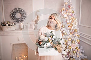 Young beautiful blonde woman decorates the Christmas tree toys.