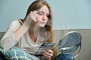 Young beautiful blonde woman doing makeup with make-up mirror