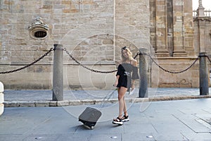 Young and beautiful blonde woman with her suitcase under her arm ready and waiting to start her holiday. Holiday and travel