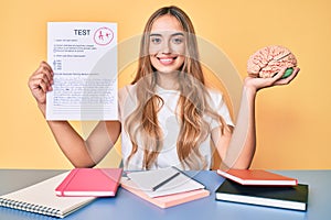 Young beautiful blonde woman holding brain and passed test smiling with a happy and cool smile on face