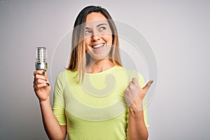 Young beautiful blonde woman holding led lightbulb over isolated white background pointing and showing with thumb up to the side