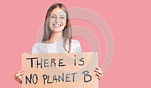 Young beautiful blonde woman holding there is no planet b banner looking positive and happy standing and smiling with a confident