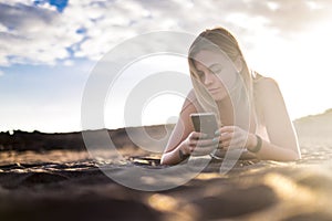 Young beautiful blonde woman lay down at the beach in vacation and lifestyle leisure activity using a smartphone to check social