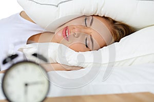 Young beautiful blonde woman lying in bed suffering from alarm c