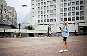 Young beautiful blonde woman piloting a drone holding a remote control