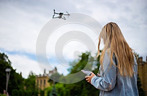 Young beautiful blonde woman piloting a drone holding a remote control