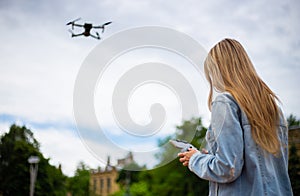 Young beautiful blonde woman piloting a drone holding a remote control