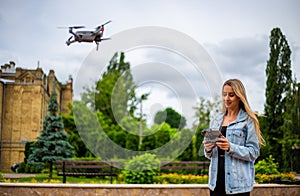 Young beautiful blonde woman piloting a drone holding a remote control