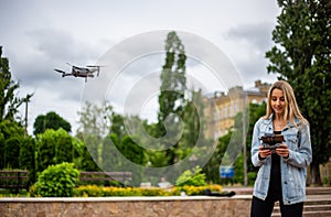 Young beautiful blonde woman piloting a drone holding a remote control