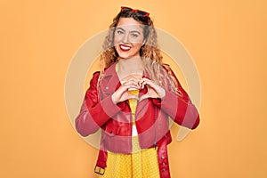 Young beautiful blonde woman pin-up with blue eyes wearing red sunglasses and jacket smiling in love showing heart symbol and