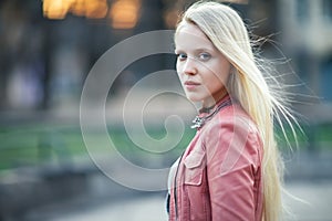 Young beautiful blonde woman portrait posing in city street on s