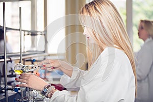 Young beautiful blonde woman researcher chemist preparing substances for chemical use with laboratory dishes.Pharmacist making ch