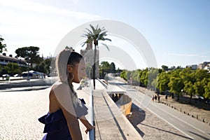 Young and beautiful blonde woman in a short dress is leaning on the railing overlooking the rest of the city. Vacation and tourism
