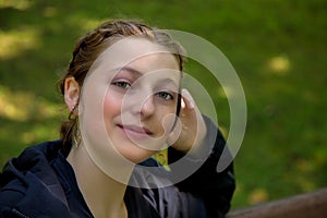 Young beautiful blonde woman sitting in a park student portrait outside