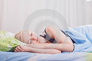 Young beautiful blonde woman sleeping in her bed in the morning