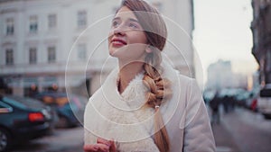 Young beautiful blonde woman is texting someone on her phone whilst walking down the street. She seems happy about what