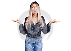 Young beautiful blonde woman wearing casual clothes crazy and mad shouting and yelling with aggressive expression and arms raised