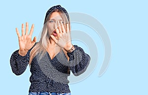Young beautiful blonde woman wearing casual clothes doing stop gesture with hands palms, angry and frustration expression
