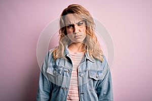 Young beautiful blonde woman wearing casual denim jacket standing over pink background skeptic and nervous, frowning upset because