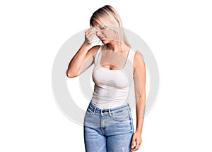 Young beautiful blonde woman wearing casual sleeveless t-shirt tired rubbing nose and eyes feeling fatigue and headache