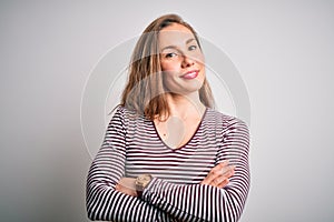 Young beautiful blonde woman wearing casual striped t-shirt over isolated white background happy face smiling with crossed arms