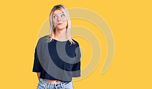 Young beautiful blonde woman wearing casual t-shirt smiling looking to the side and staring away thinking