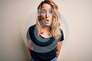 Young beautiful blonde woman wearing casual t-shirt standing over isolated white background afraid and shocked with surprise