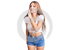 Young beautiful blonde woman wearing casual white tshirt hand on mouth telling secret rumor, whispering malicious talk