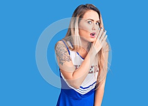 Young beautiful blonde woman wearing cheerleader uniform hand on mouth telling secret rumor, whispering malicious talk
