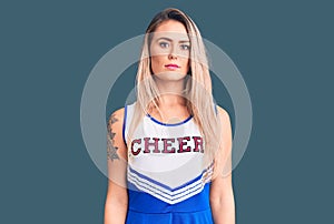 Young beautiful blonde woman wearing cheerleader uniform looking sleepy and tired, exhausted for fatigue and hangover, lazy eyes