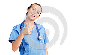 Young beautiful blonde woman wearing doctor uniform and stethoscope doing happy thumbs up gesture with hand