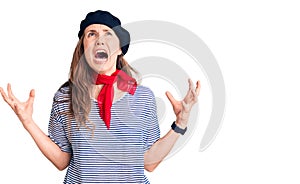 Young beautiful blonde woman wearing french beret and striped t-shirt crazy and mad shouting and yelling with aggressive