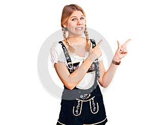 Young beautiful blonde woman wearing oktoberfest dress pointing aside worried and nervous with both hands, concerned and surprised