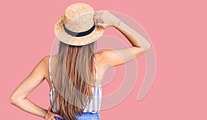 Young beautiful blonde woman wearing summer hat backwards thinking about doubt with hand on head