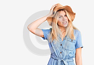 Young beautiful blonde woman wearing summer hat and dress confuse and wonder about question