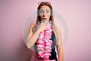 Young beautiful blonde woman wearing swimsuit and floral Hawaiian lei over pink background Looking fascinated with disbelief,