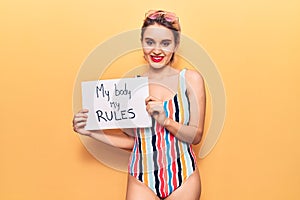 Young beautiful blonde woman wearing swimwear holding my body my rules banner looking positive and happy standing and smiling with
