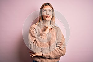 Young beautiful blonde woman wearing winter wool sweater over pink isolated background Thinking concentrated about doubt with