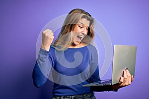 Young beautiful blonde woman working using laptop over isolated purple background screaming proud and celebrating victory and