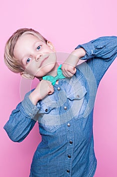 Young beautiful boy with blue shirt and butterfly tie. Studio portrait over pink background.