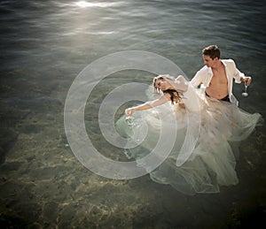 Young beautiful bridal couple having fun together at the beach